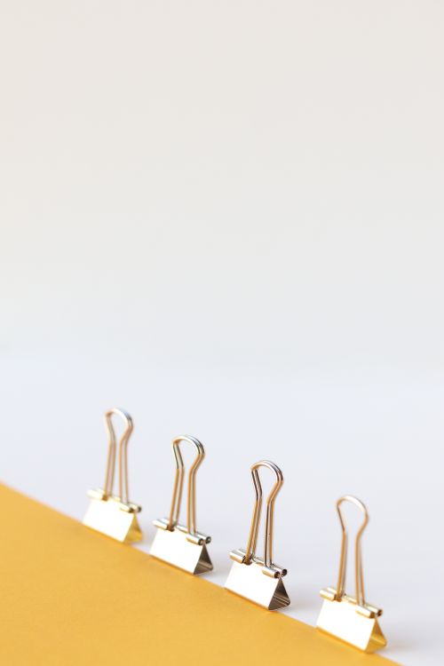 Free Minimalist arrangement of binder clips on a yellow surface with ample copyspace. Stock Photo