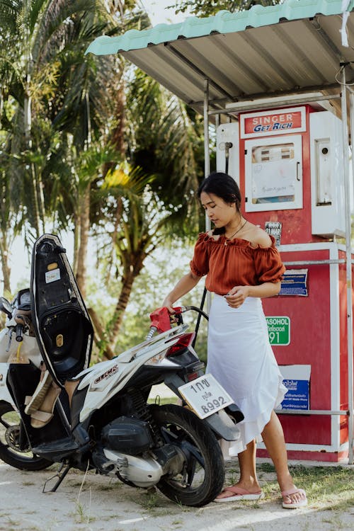 A Woman in Brown Off Shoulder Top Refilling a Gas on Her Motorcycle 