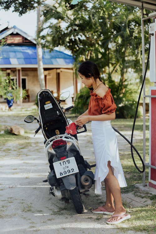 Gratis lagerfoto af asiatisk kvinde, benzinpumpe, fra siden