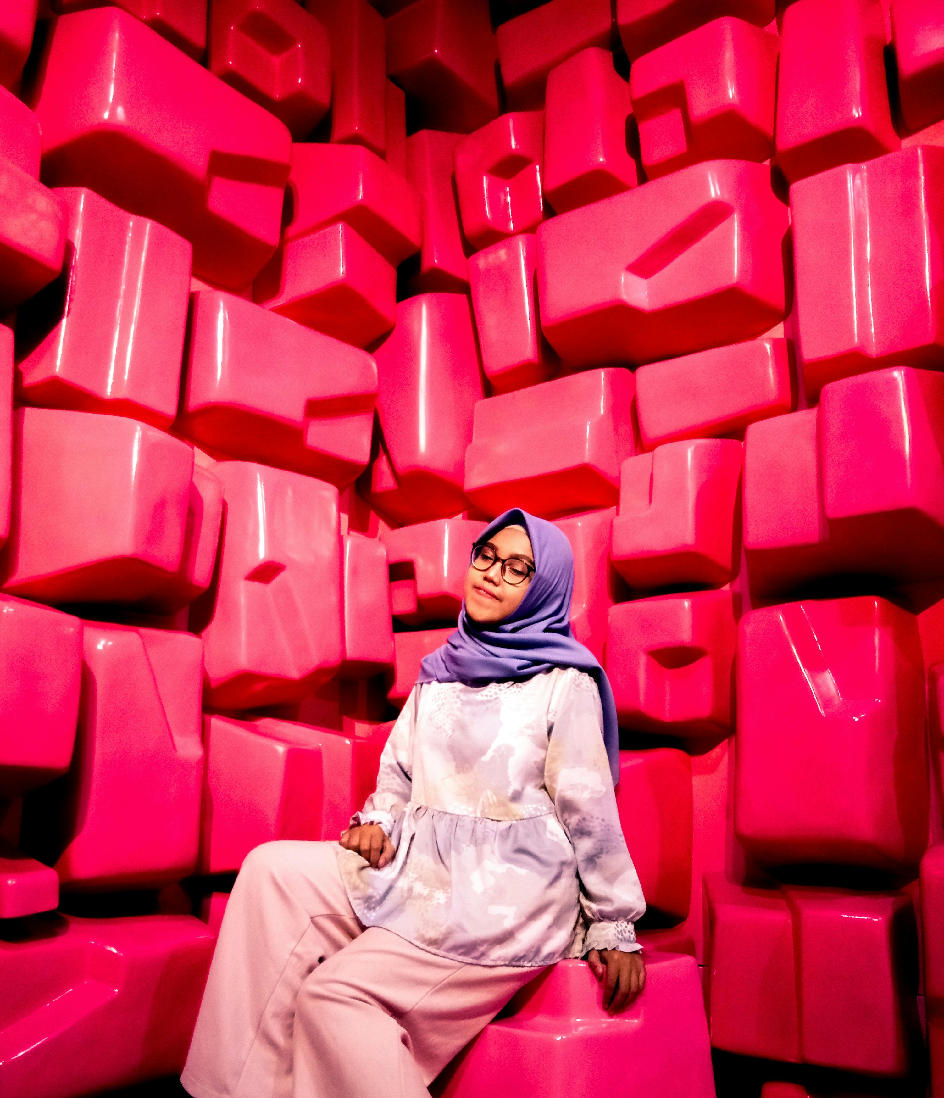 woman in brown hijab sitting on red plastic chair