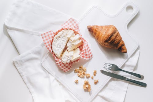 White Cheese Beside a Croissant on White Board