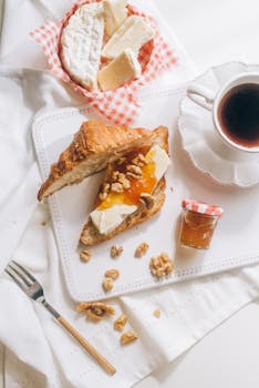 Enjoy a gourmet breakfast featuring a croissant with cheese and jam, paired with coffee.