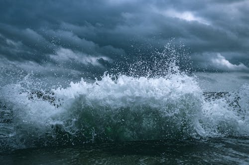 Ocean Waves Under Cloudy Sky Crashing on Shore