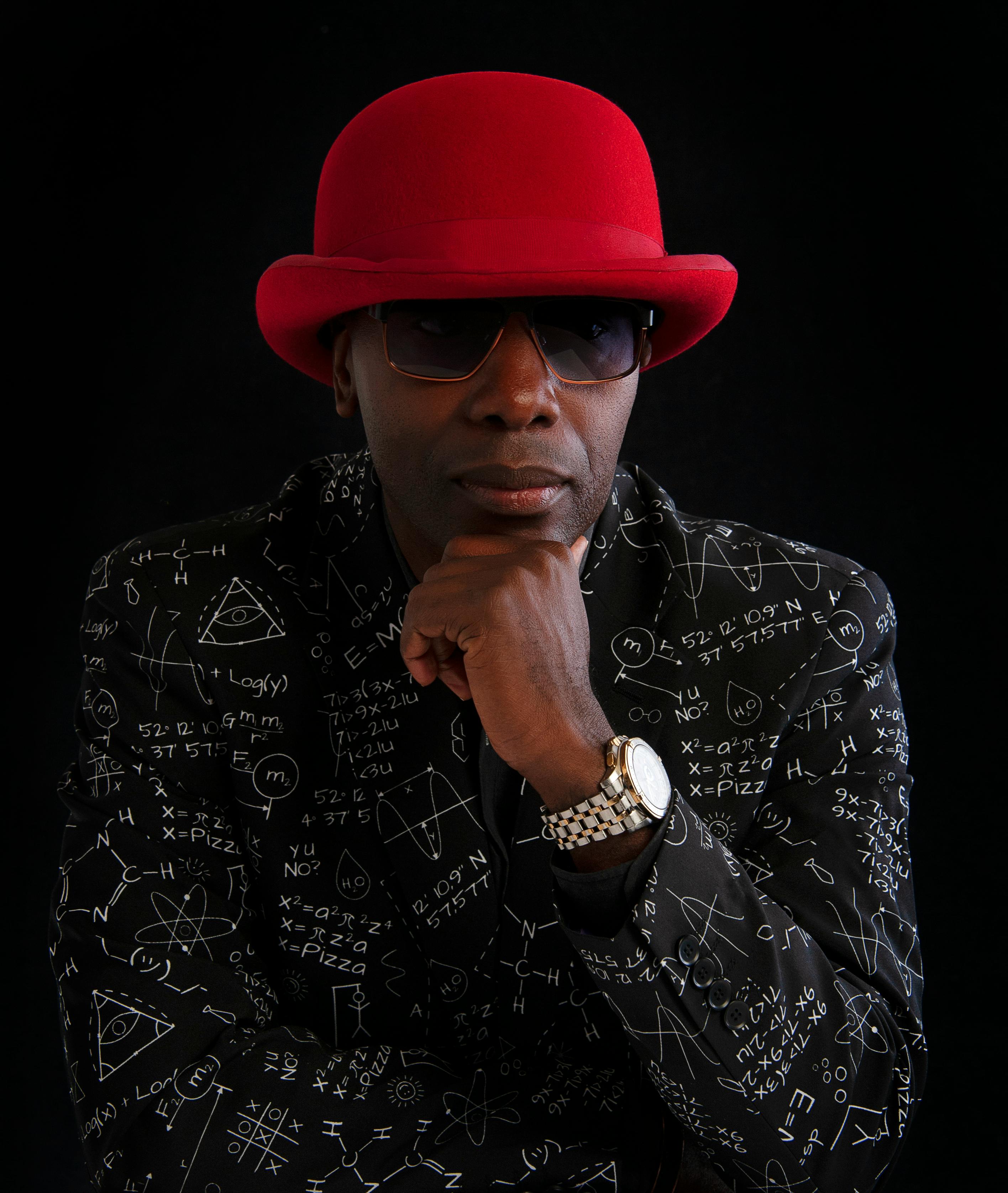 Portrait of a man wearing a red hat and a pattern suit with equations on a black background.