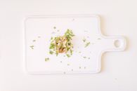从顶视图拍摄白色切菜板上的草药和切片食物，营造极简主义氛围