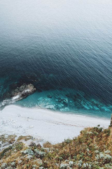 Stunning aerial view of a white sand beach with turquoise waters and rocky formations.
