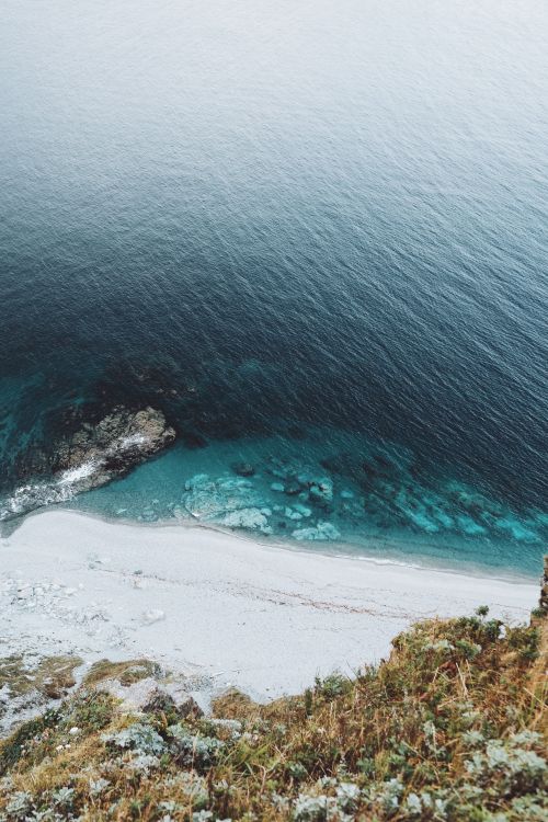 Free Stunning aerial view of a white sand beach with turquoise waters and rocky formations. Stock Photo