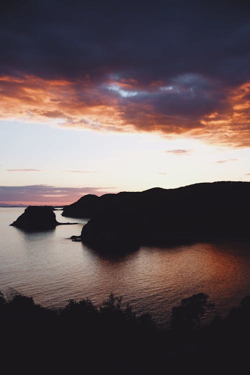 Silhouette of Mountain Beside Body of Water during Sunset