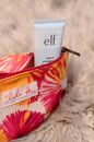 Colorful beauty bag with tube of rejuvenating cream placed on light pink fluffy cloth