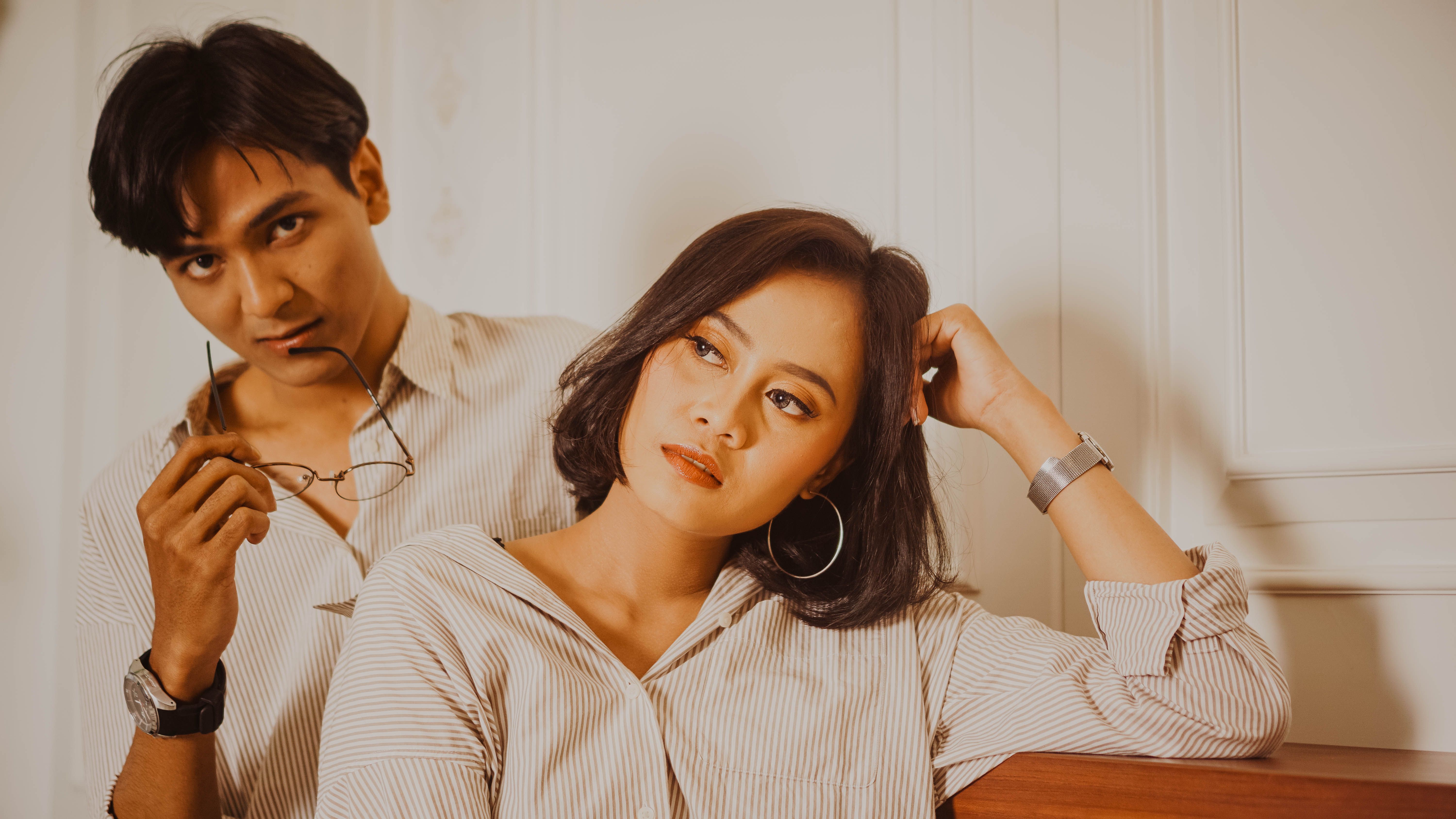 Chic couple in stylish outfits posing indoors, embodying modern fashion and elegance.