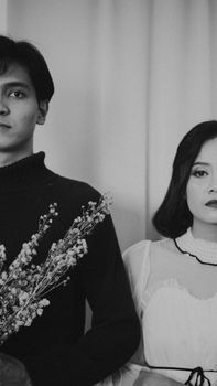 Elegant black and white portrait of a couple holding flowers, showcasing artistic expression.