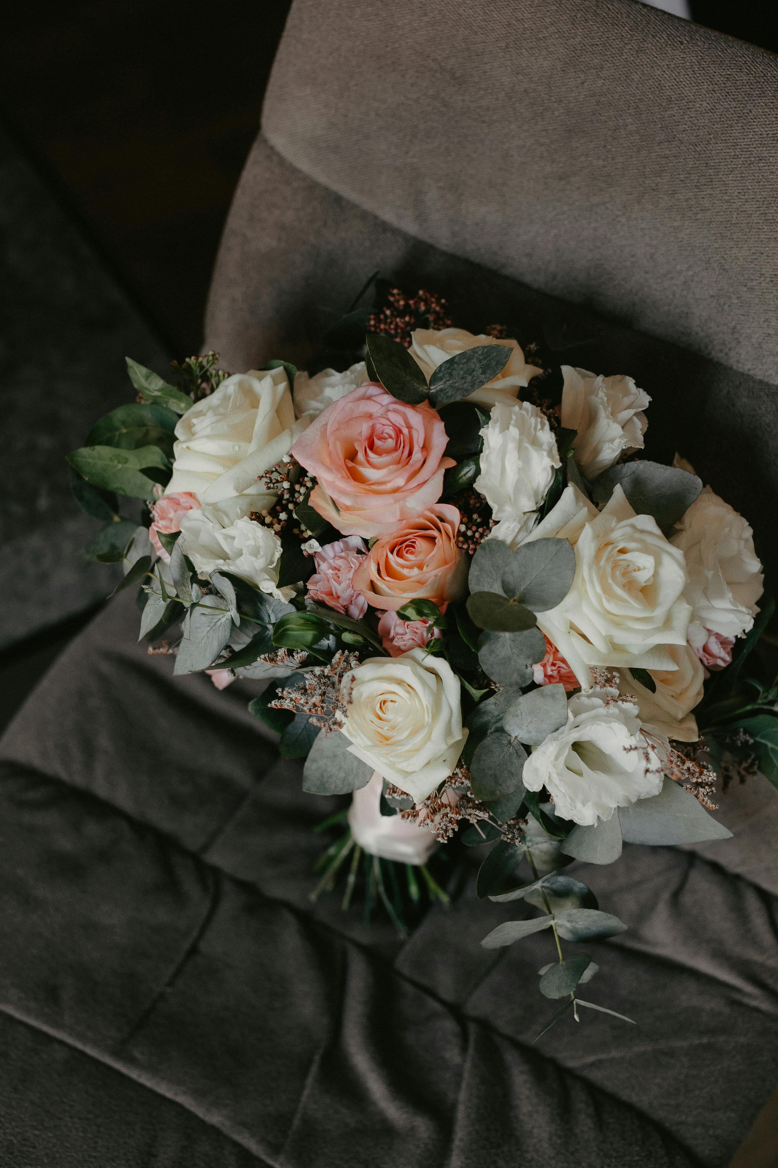 From above of fresh bunch of blooming flowers with green leaves on gray cozy sofa