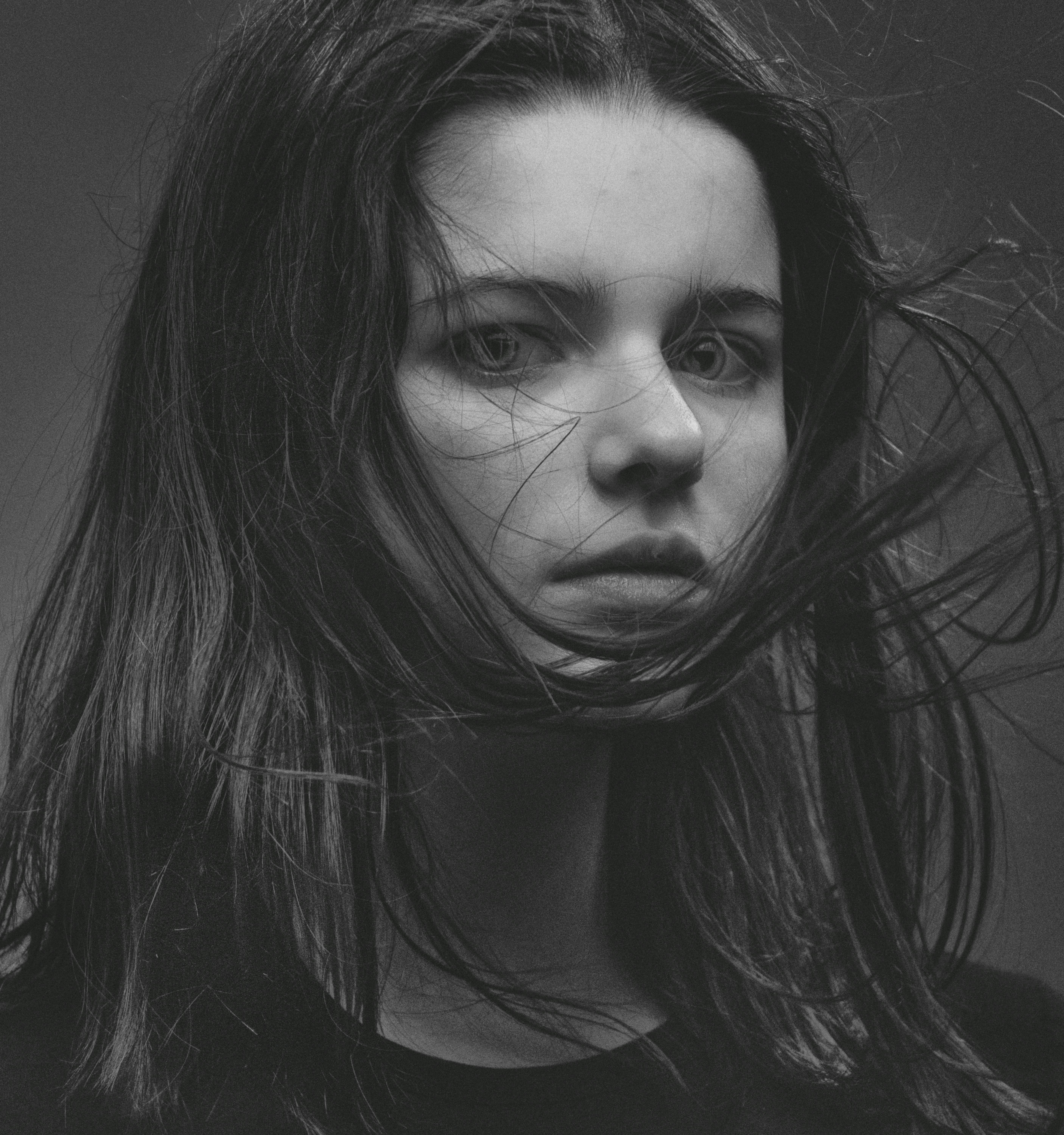 一幅年轻女子的单色肖像，她目光炯炯，发丝随风飘动