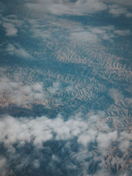 Free A breathtaking aerial shot showcasing mountain peaks through scattered clouds. Stock Photo