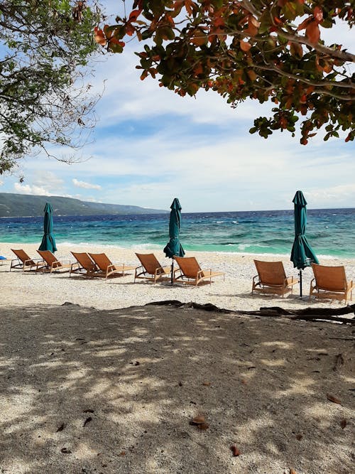 Beach Lounge Chairs And Umbrellas By The Seashore 