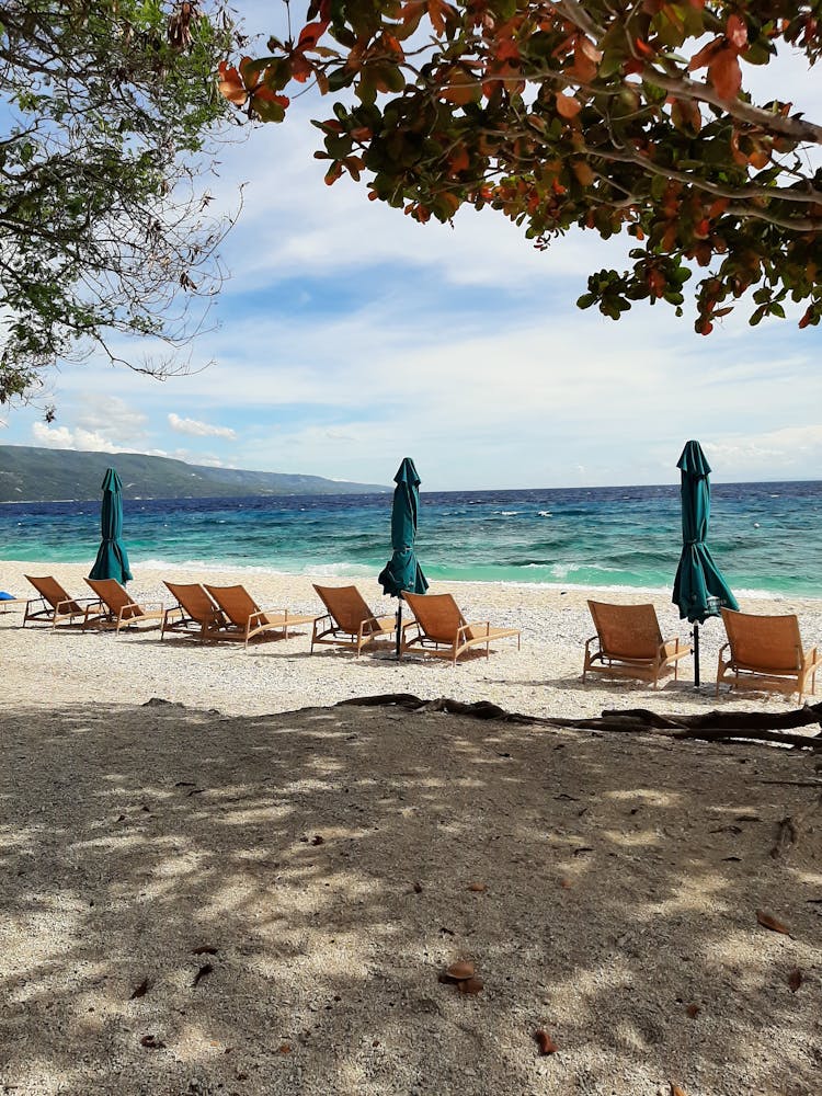 Beach Lounge Chairs And Umbrellas By The Seashore 