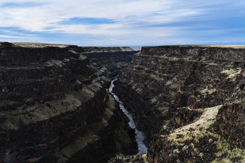 Free Breathtaking view of a deep canyon with a river cutting through, under a vibrant sky in Idaho. Stock Photo