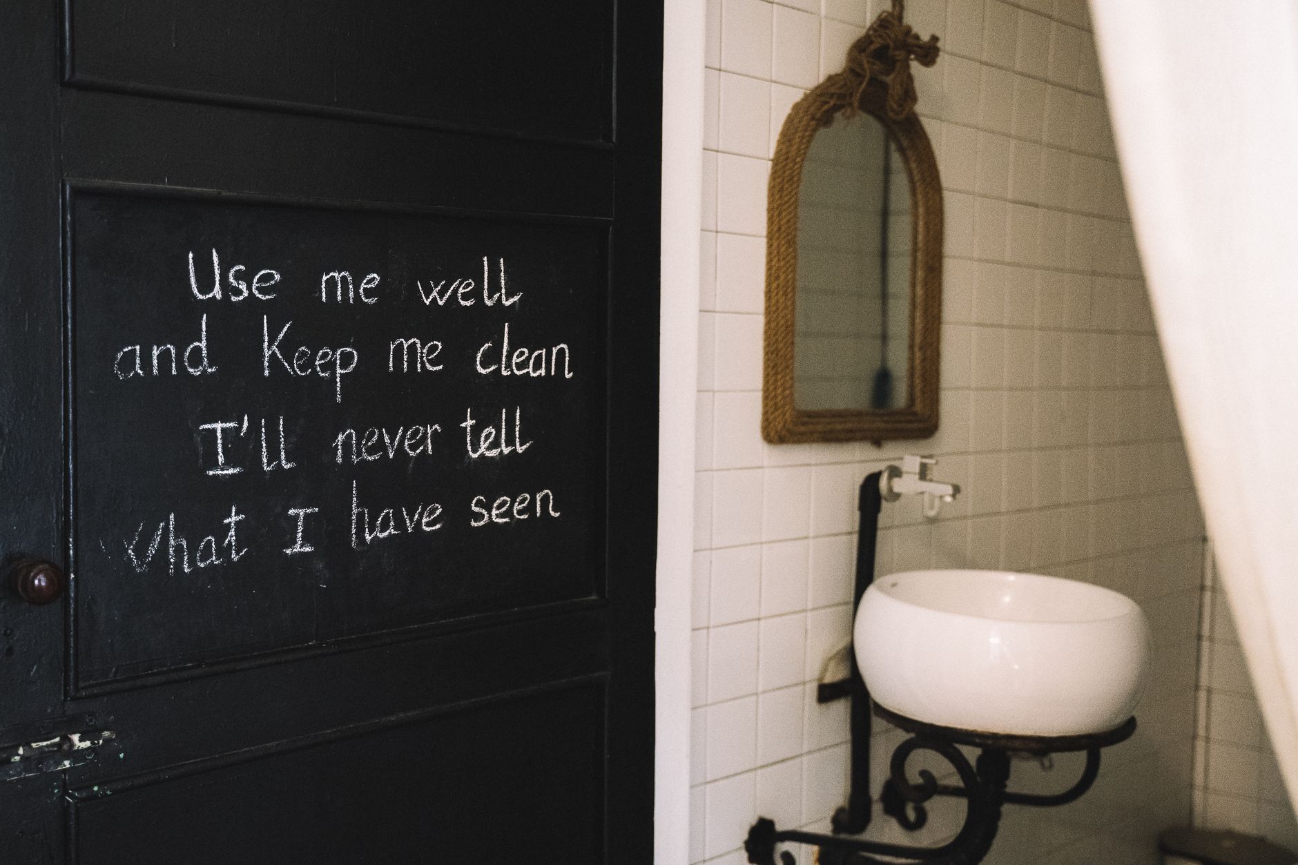 Rustic bathroom interior featuring chalkboard quote and vintage mirror.