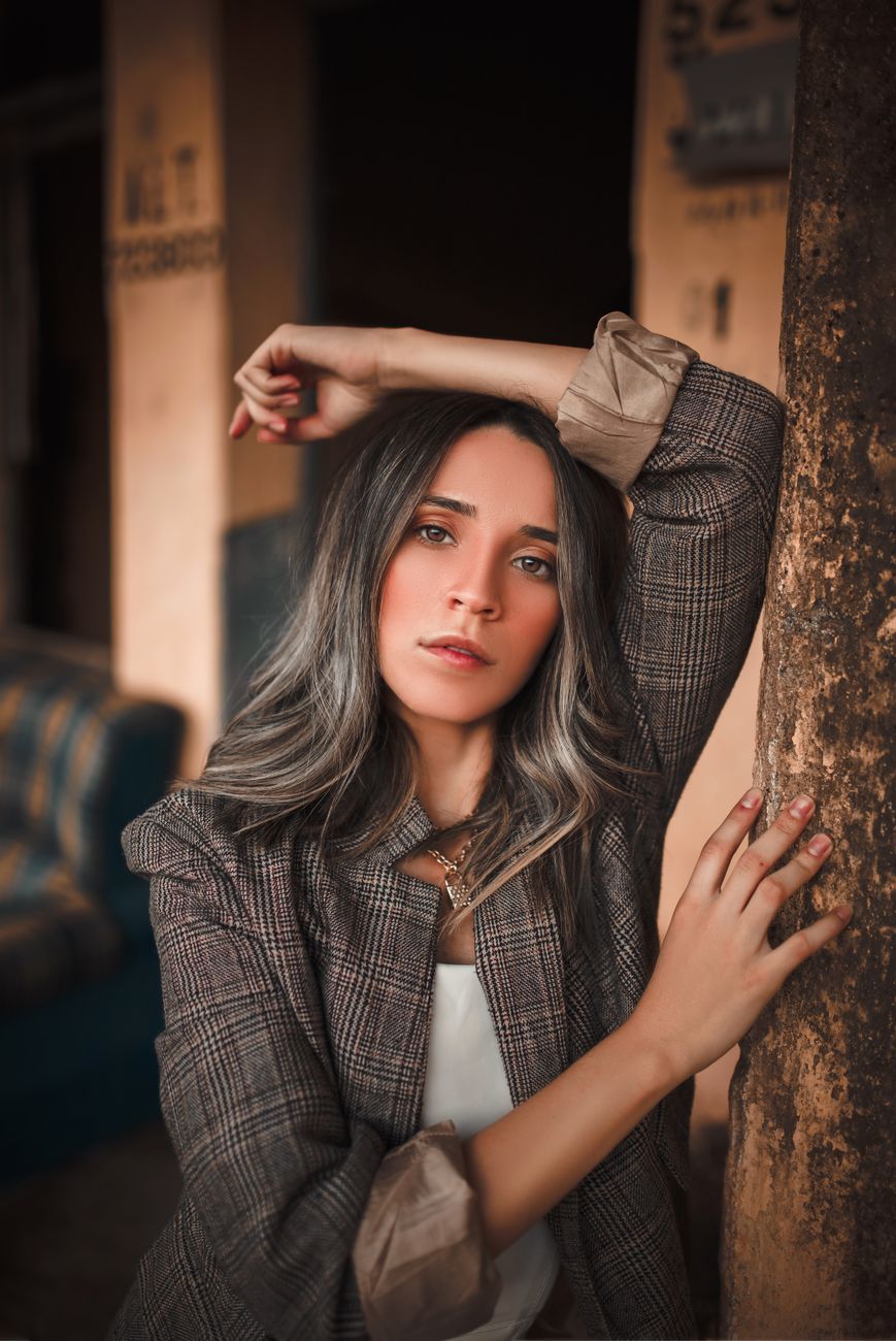 Portrait of a fashionable woman posing indoors with a confident expression, showcasing elegant attire.