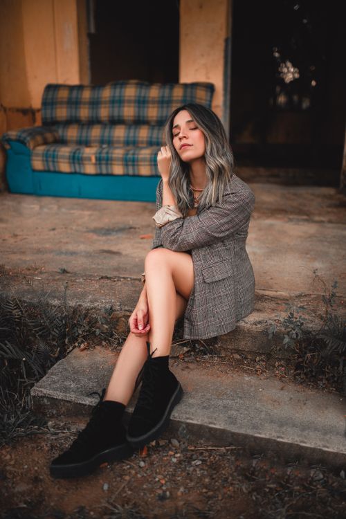 Free Fashionable woman in black boots sitting outdoors with eyes closed, capturing a serene moment. Stock Photo