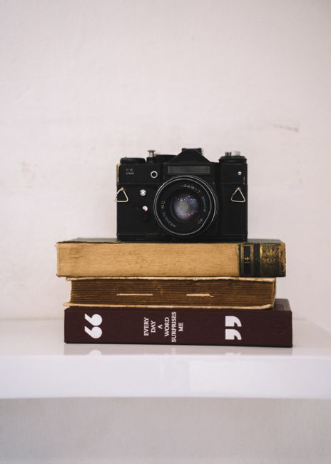 An antique film camera rests atop a stack of books, creating a classic still life scene.