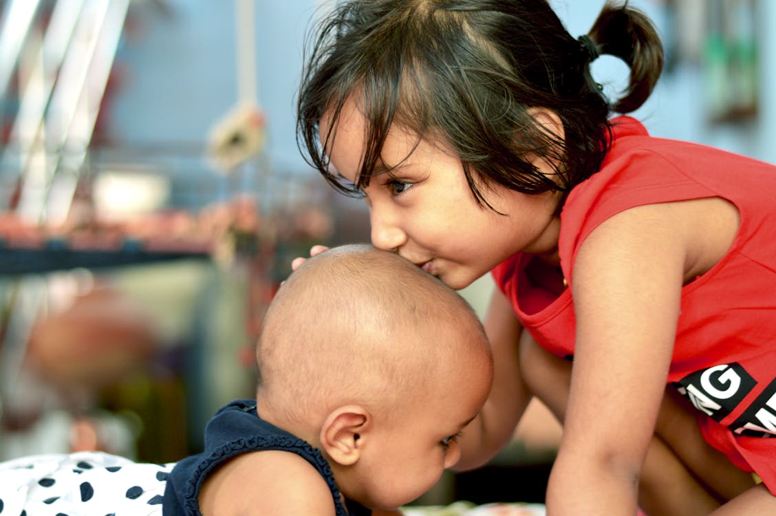 Free Girl in Red Tank Top Kissing Baby Stock Photo