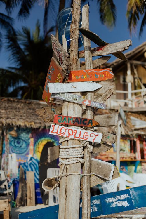 Free Vibrant wooden signpost with multiple destination signs at a colorful tropical beach bar. Stock Photo