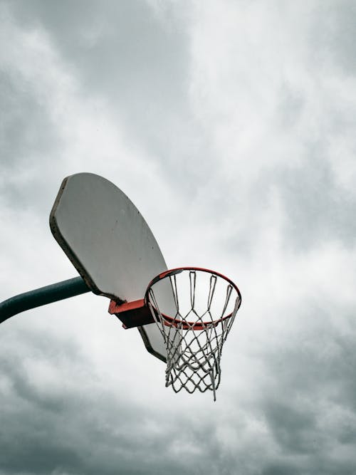 Basketball hoop on wooden backboard against overcast sky · Free