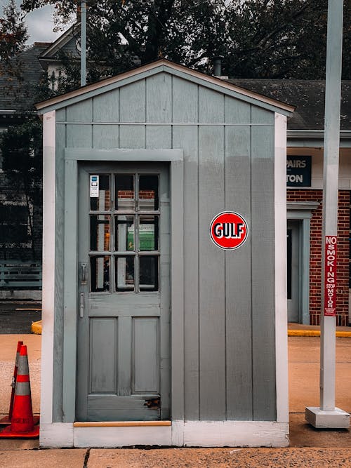 Exterior of small gray wooden house with door located on street in daytime