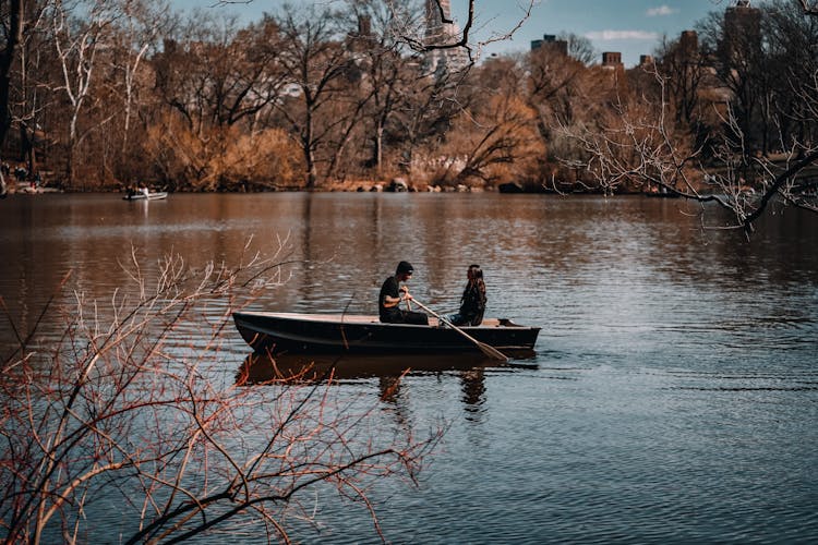 Couple Sitting In Boat Floating On Lake