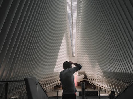 Back view of unrecognizable man standing and taking photo of contemporary World Trade Center Transportation Hub located in New York