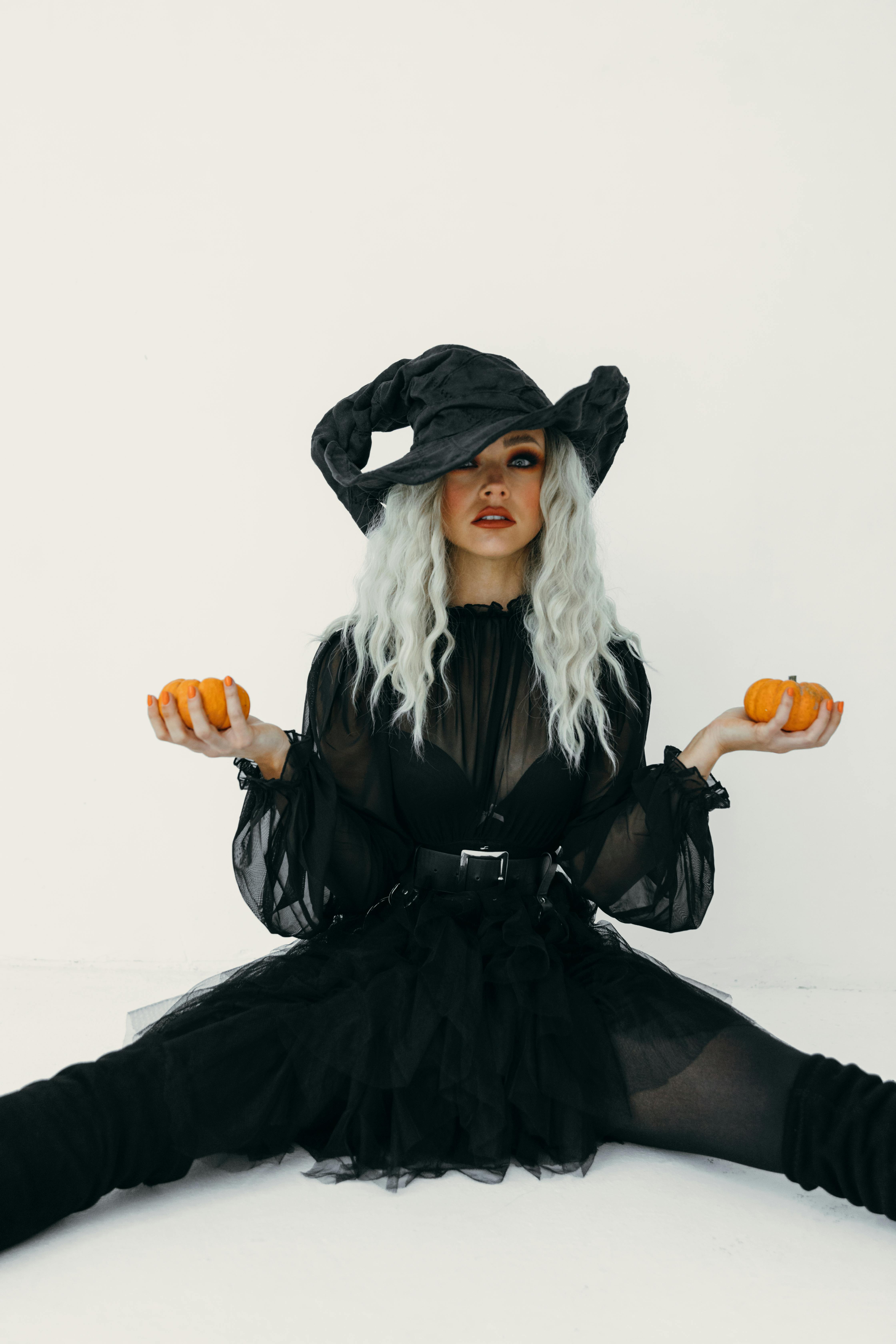 woman in black dress holding two pumpkins