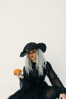 一位身着女巫服装、手持迷你南瓜的女性肖像，是万圣节主题的理想选择