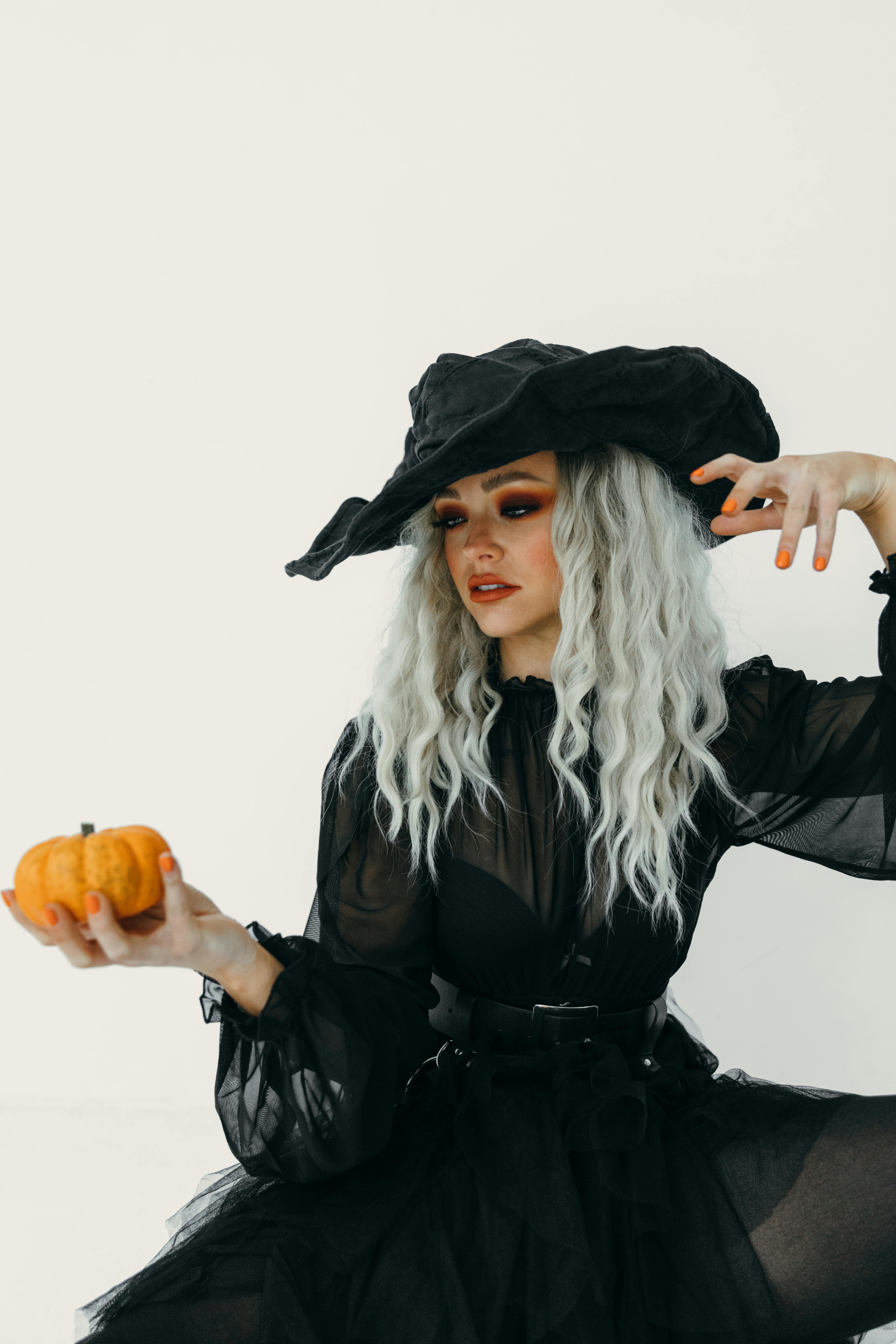 woman in witch costume holding a pumpkin