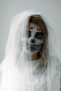 A spooky portrait of a bride with skull makeup wearing a veil, perfect for Halloween themes.