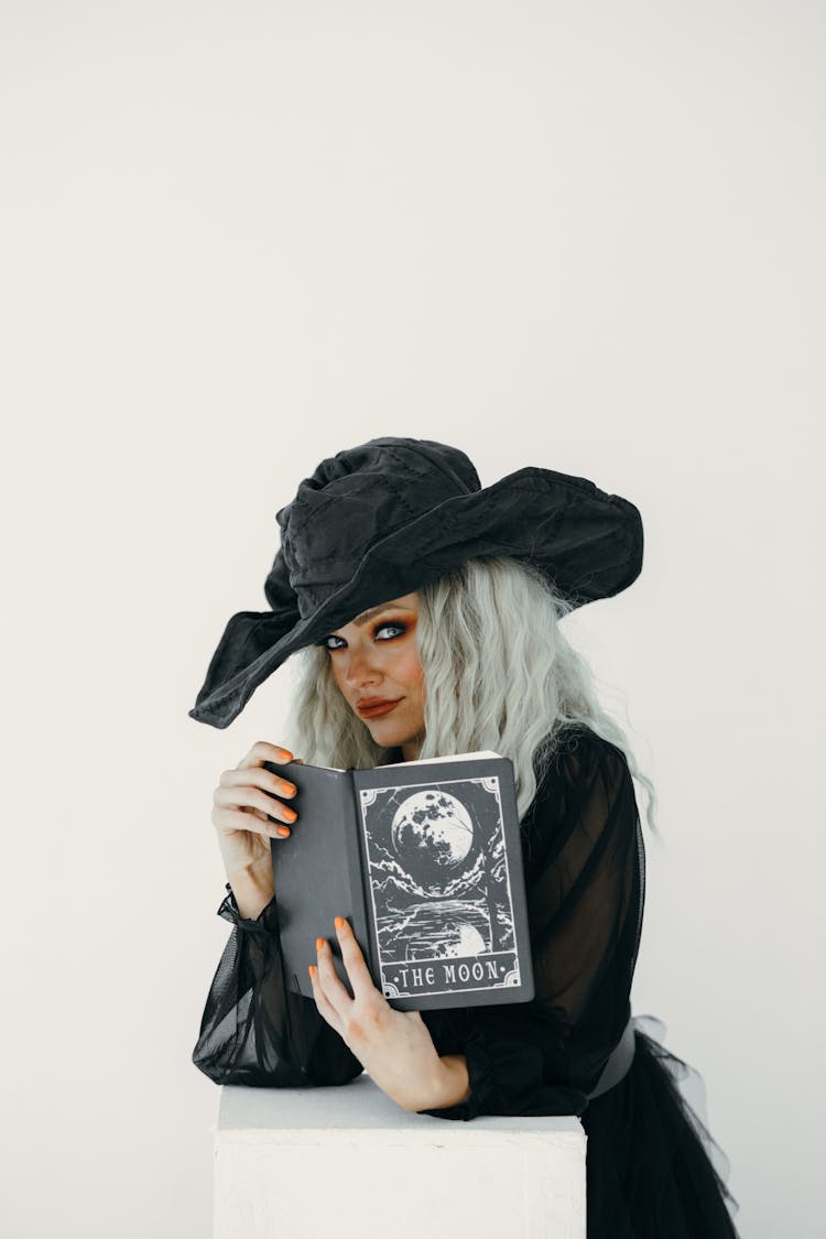 Woman In Witch Costume Holding A Black Book