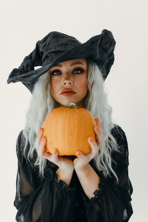 Free Woman in A Witch Costume Holding A Big Pumpkin Stock Photo
