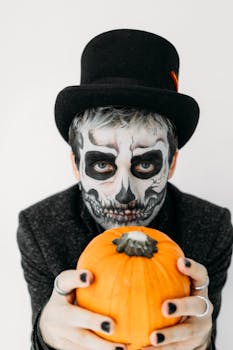A spooky portrait of a person in skull makeup holding a pumpkin, perfect for Halloween themes.