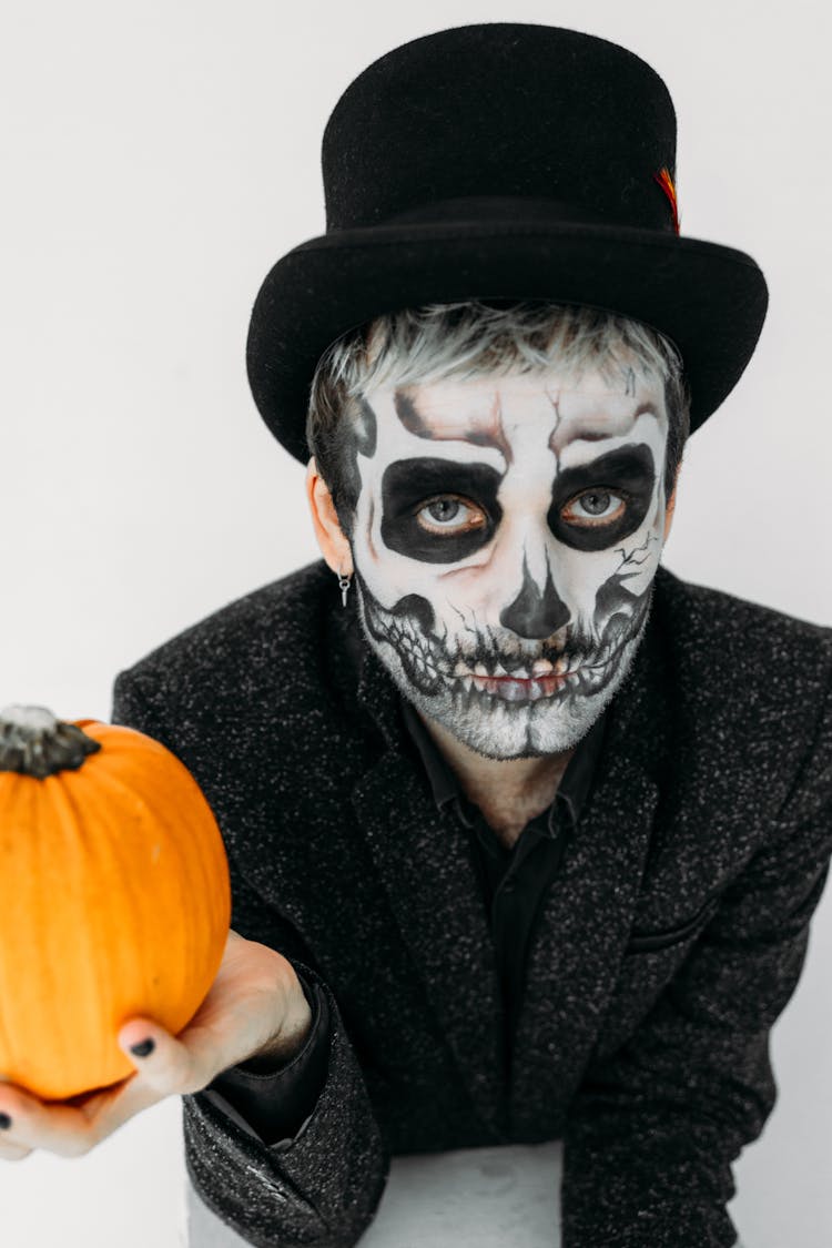 Man With Scary Face Paint Holding A Pumpkin 