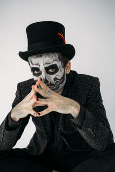 这幅肖像画中的男人妆容和服装怪异，脸上画着骷髅图案，头戴一顶礼帽