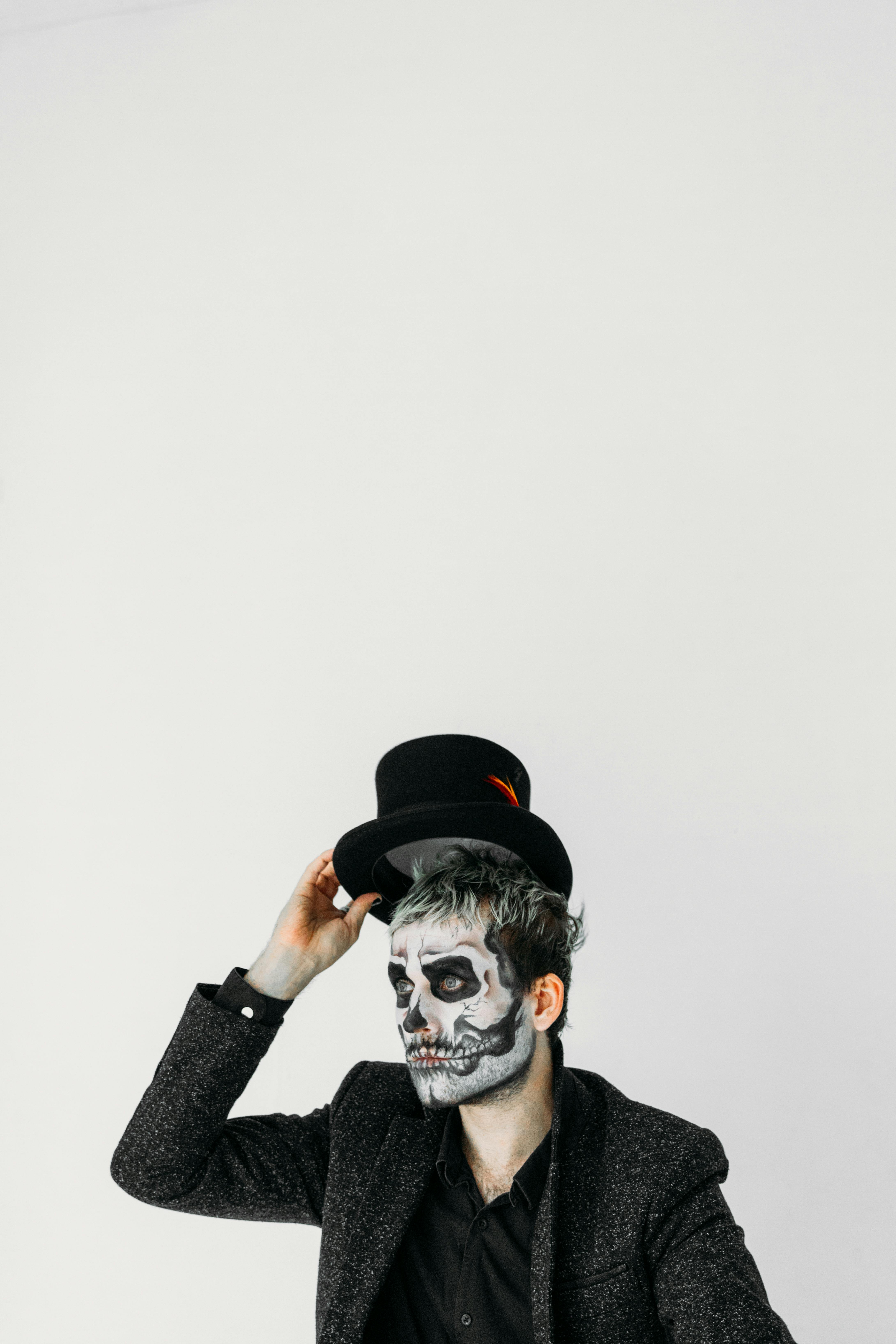 man with skull face paint holding his hat