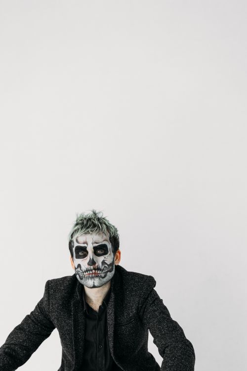 Free Man with skull makeup in black suit, capturing creepy Halloween vibes. Stock Photo