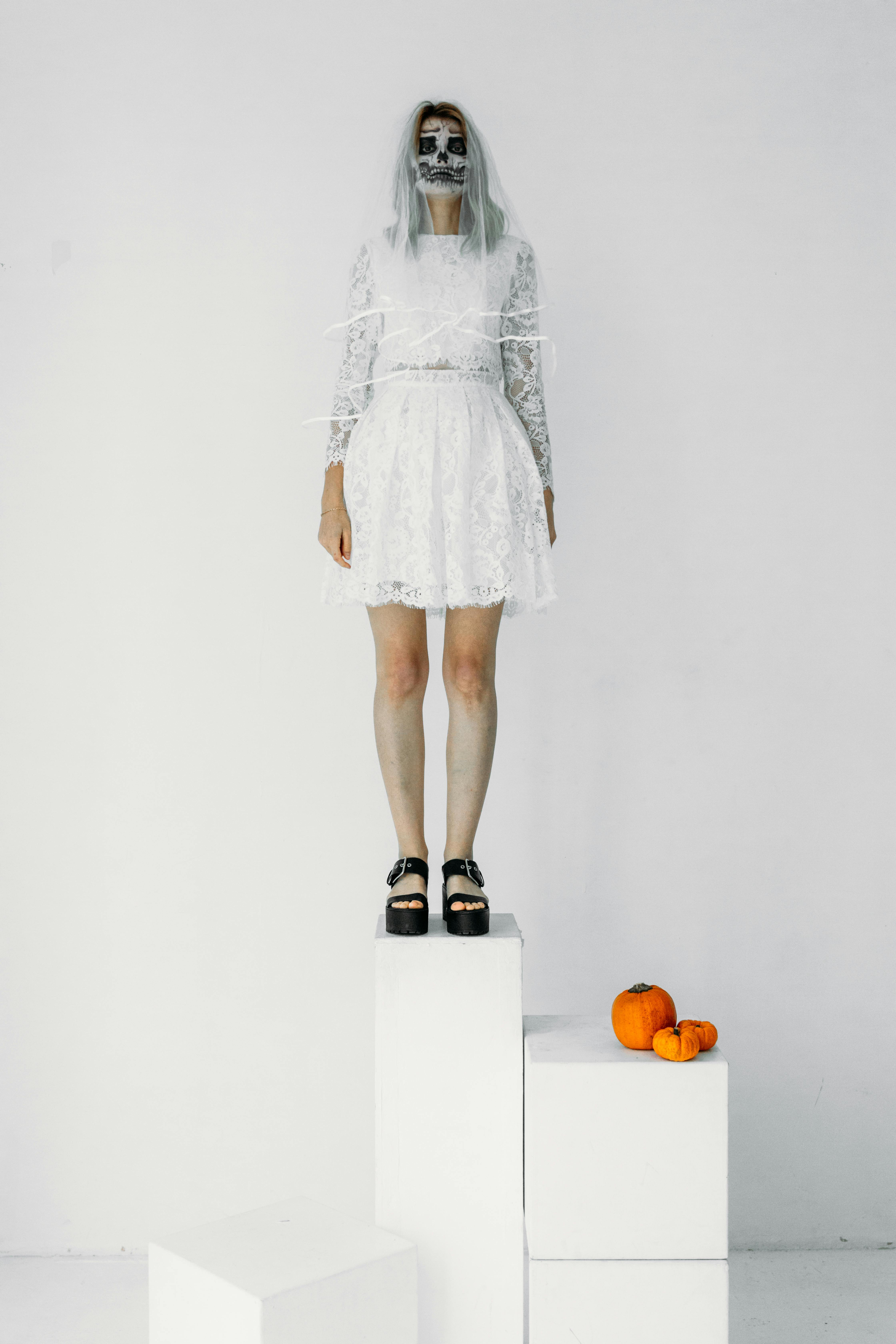 一位头骨化妆、令人毛骨悚然的新娘形象，在室内与南瓜合影