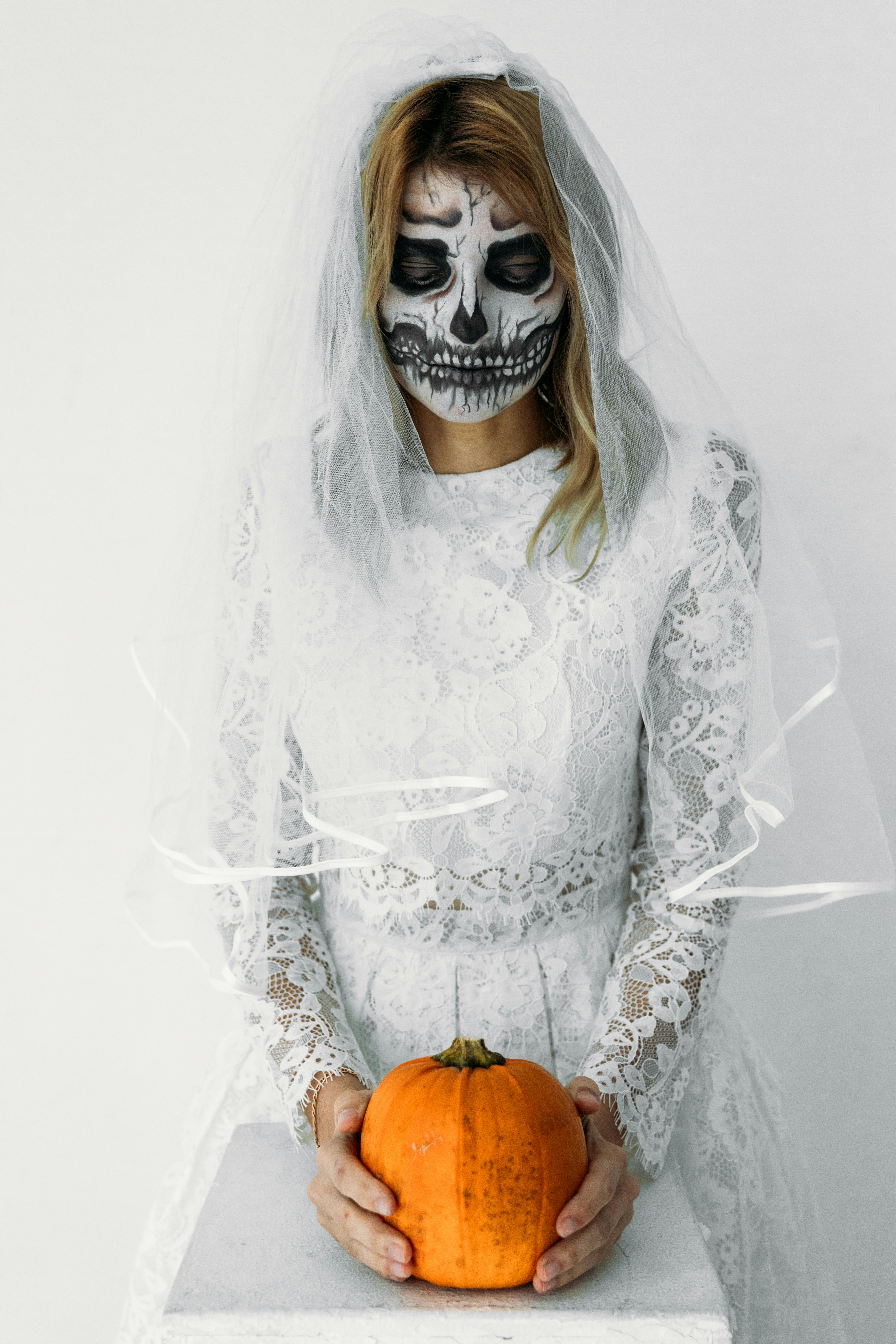 woman in white lace dress holding pumpkin