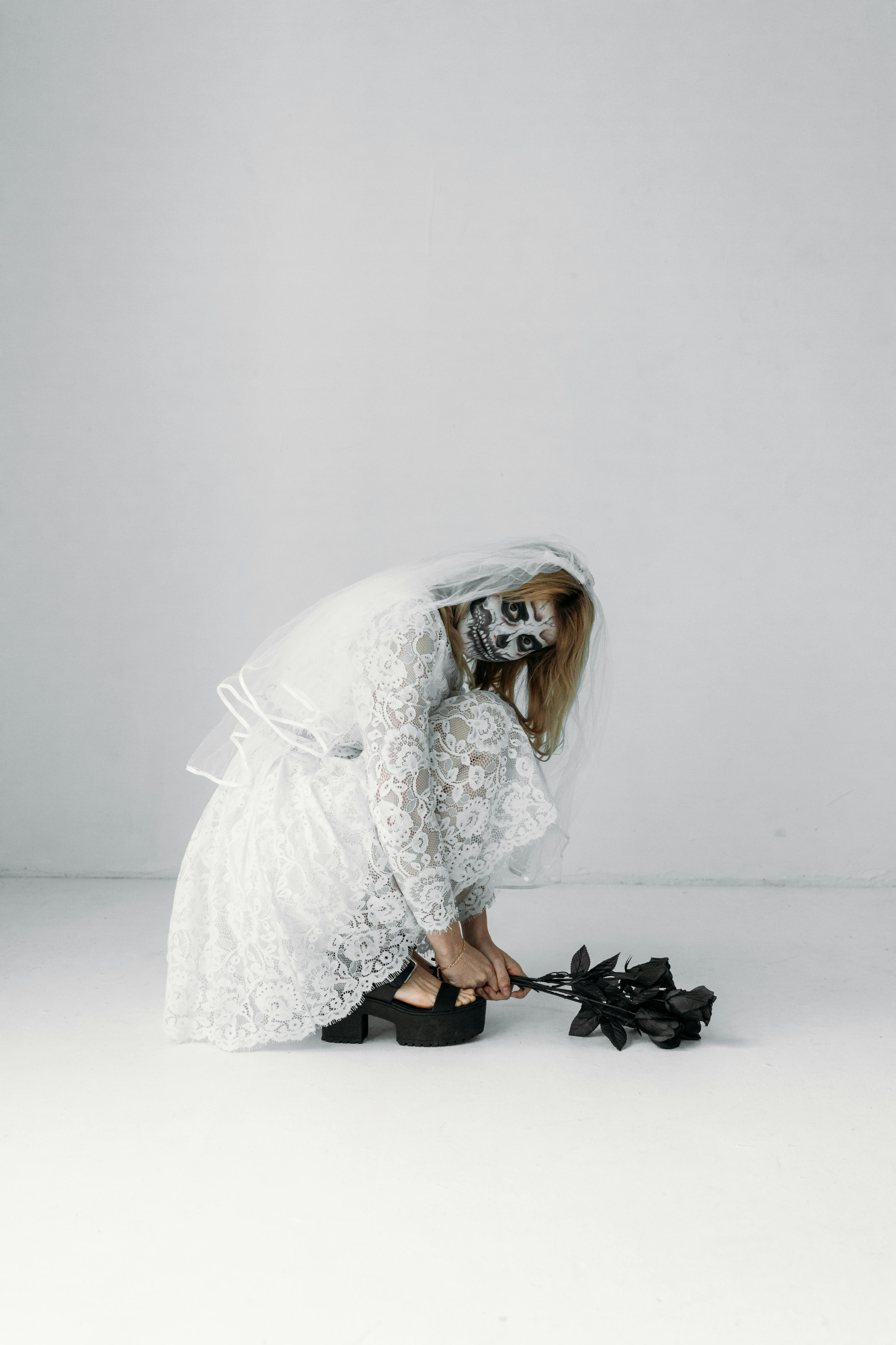 woman in white dress holding a bunch of black roses