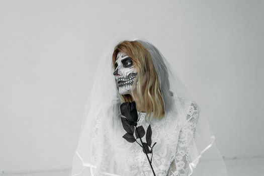 一位身着蕾丝婚纱、头戴面纱的女子，脸上画着骷髅妆容，手持一朵黑玫瑰，构成了一幅令人难忘的新娘肖像