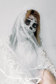 一个戴着面纱的女人，穿着画有骷髅脸图案的婚纱