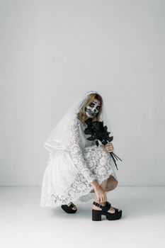 一个穿着蕾丝连衣裙、脸上画着彩绘的新娘，在室内摆弄着黑色花朵，样子令人毛骨悚然