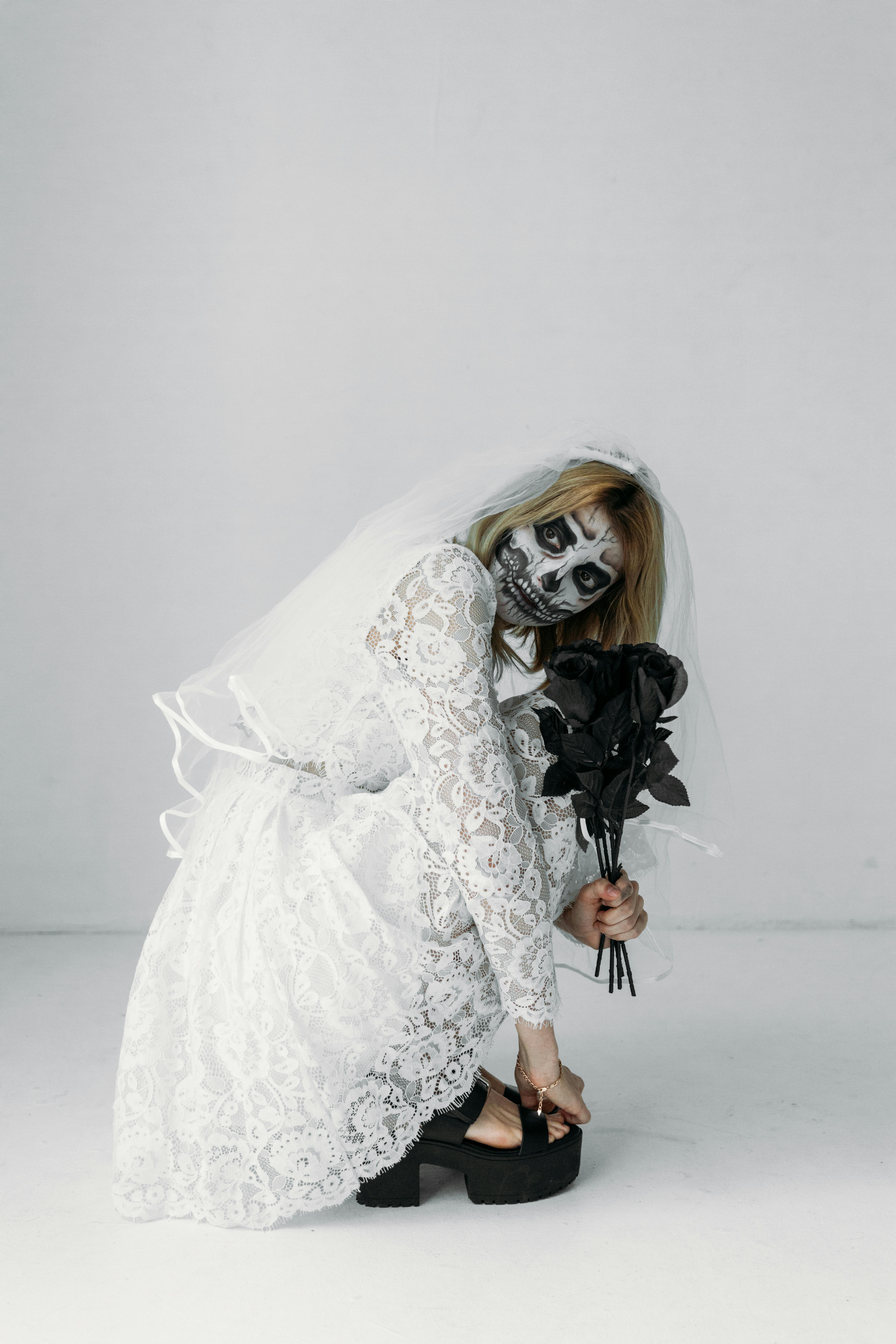 woman in white lace wedding dress holding bouquet of flowers