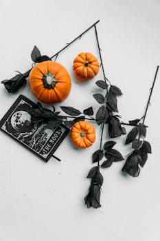 Halloween-themed flatlay with pumpkins, black roses, and a moon-themed card for spooky decor.